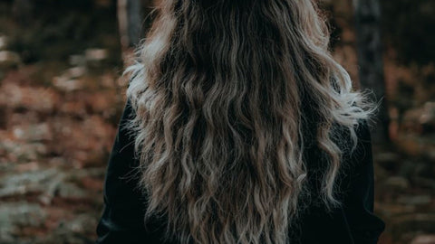 Femme de dos aux cheveux longs et fournis, illustrant une cure de biotine cheveux avant après